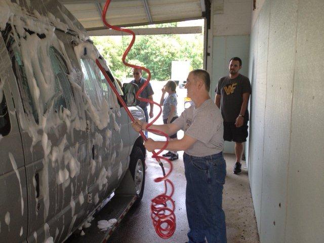 Individuals and staff washing the PEACE Van before detailing it.
